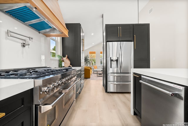 kitchen with light hardwood / wood-style flooring, extractor fan, vaulted ceiling, and appliances with stainless steel finishes