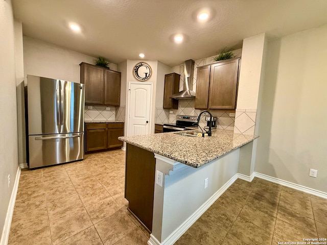 kitchen featuring light stone countertops, sink, wall chimney range hood, decorative backsplash, and appliances with stainless steel finishes