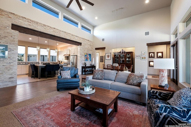 living room featuring ceiling fan, wood-type flooring, and a towering ceiling