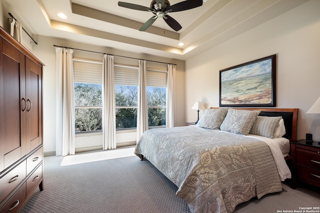 bedroom featuring light carpet, a raised ceiling, and ceiling fan