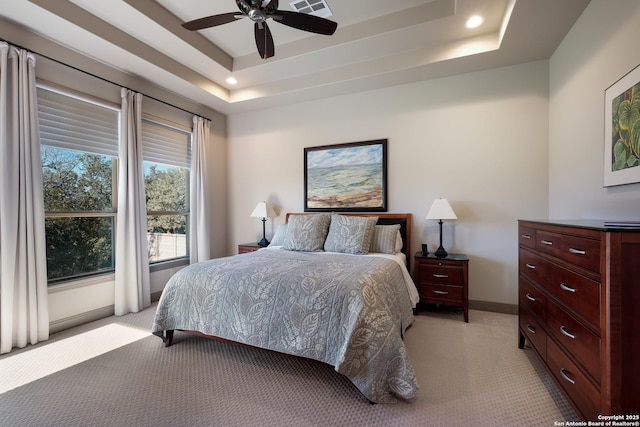 bedroom featuring ceiling fan, a raised ceiling, and light colored carpet