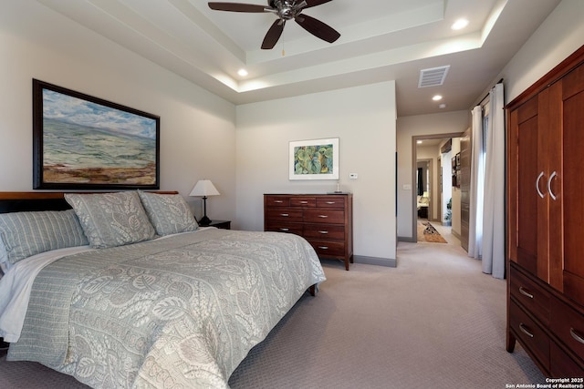 carpeted bedroom with a closet, a tray ceiling, and ceiling fan