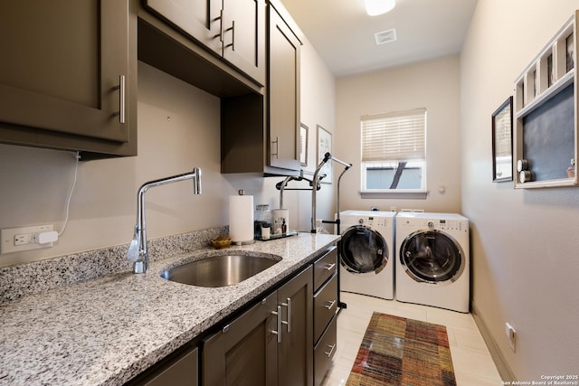 laundry area featuring washer and clothes dryer, sink, light tile patterned floors, and cabinets