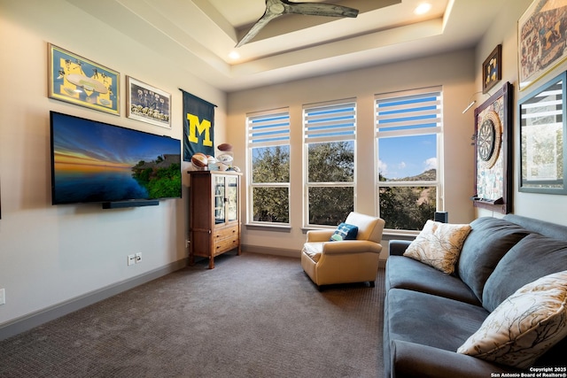 living room featuring carpet, a raised ceiling, and ceiling fan