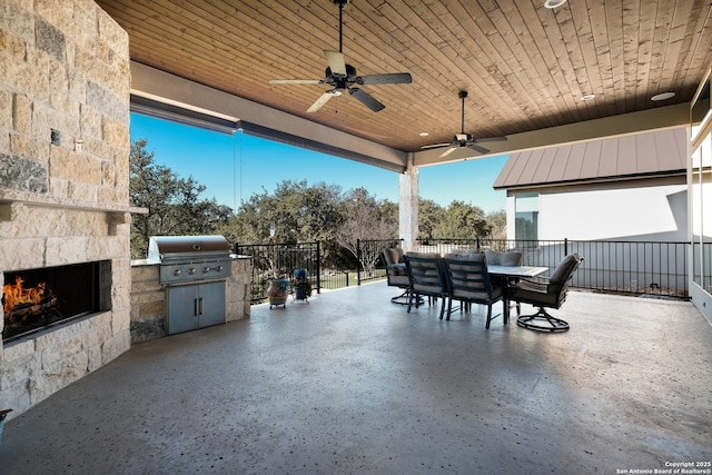 view of patio with an outdoor stone fireplace, area for grilling, and ceiling fan