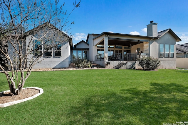 rear view of property featuring a lawn and ceiling fan