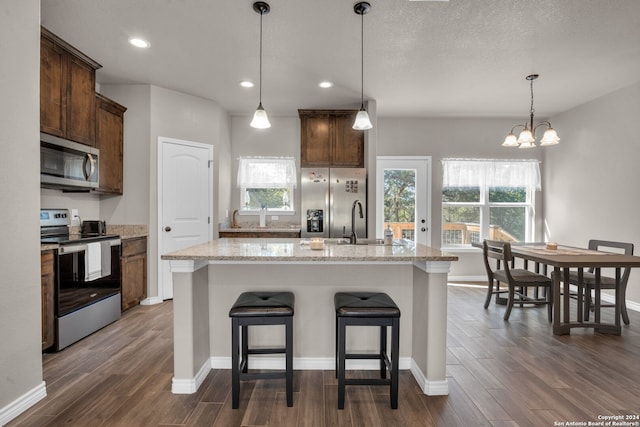 kitchen featuring appliances with stainless steel finishes, dark hardwood / wood-style flooring, a center island with sink, and a wealth of natural light