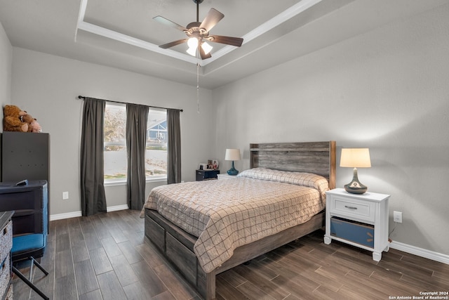 bedroom with ceiling fan, dark hardwood / wood-style flooring, and a tray ceiling