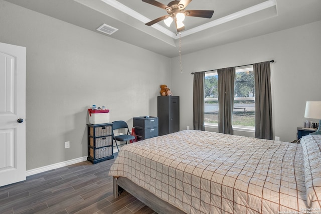 bedroom with ceiling fan, dark hardwood / wood-style floors, and a tray ceiling