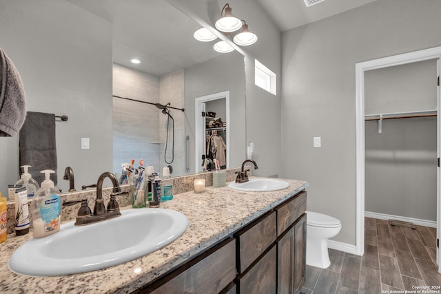 bathroom featuring vanity, toilet, a tile shower, and wood-type flooring