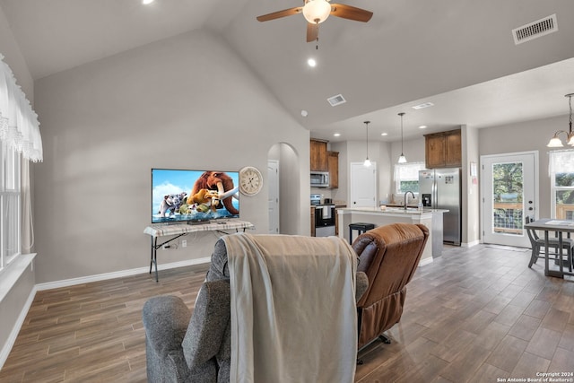 living room with dark hardwood / wood-style floors, ceiling fan with notable chandelier, and high vaulted ceiling