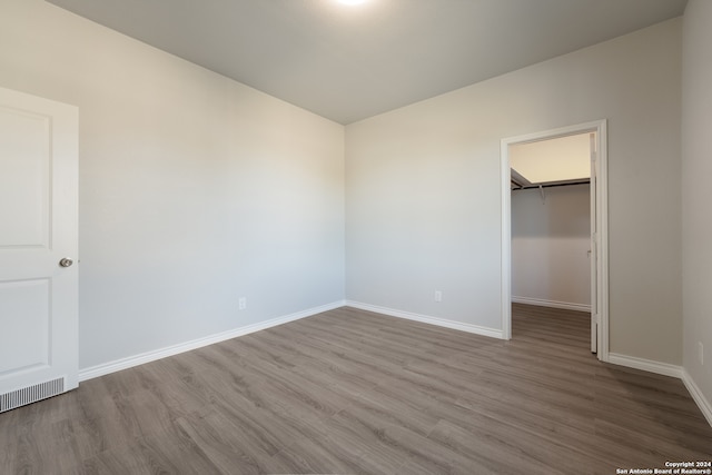 unfurnished bedroom with light wood-type flooring, a spacious closet, and a closet