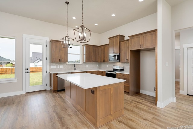 kitchen with a healthy amount of sunlight, light hardwood / wood-style flooring, a kitchen island, and stainless steel appliances