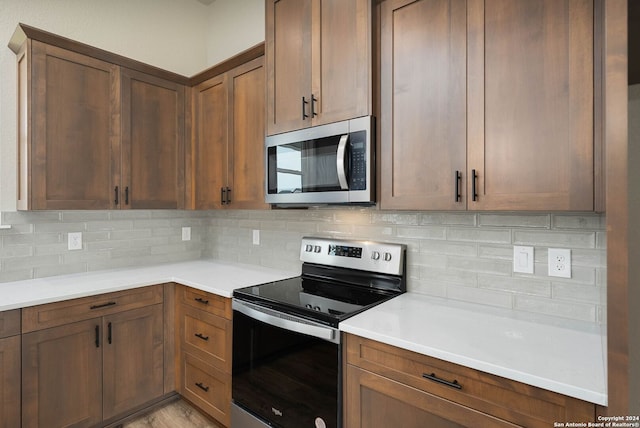 kitchen with light wood-type flooring, backsplash, and appliances with stainless steel finishes