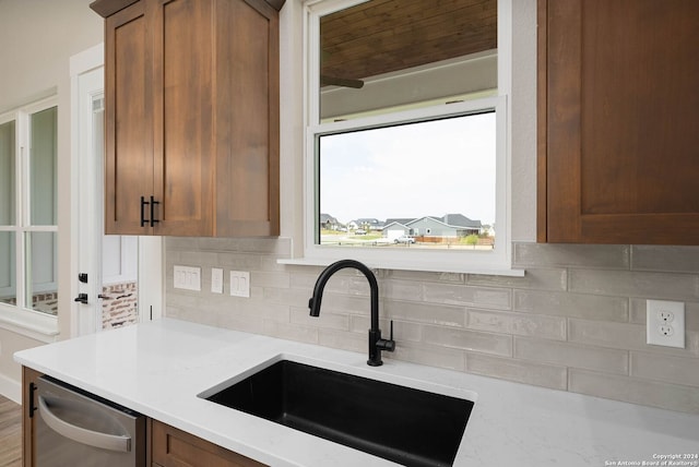 kitchen with dishwasher, decorative backsplash, light stone countertops, and sink