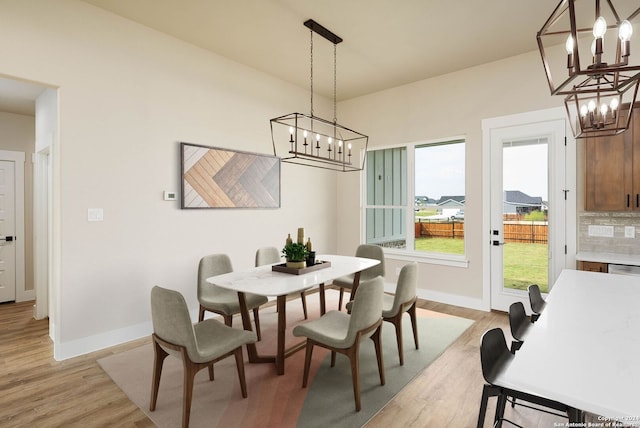 dining area with light hardwood / wood-style flooring and a notable chandelier