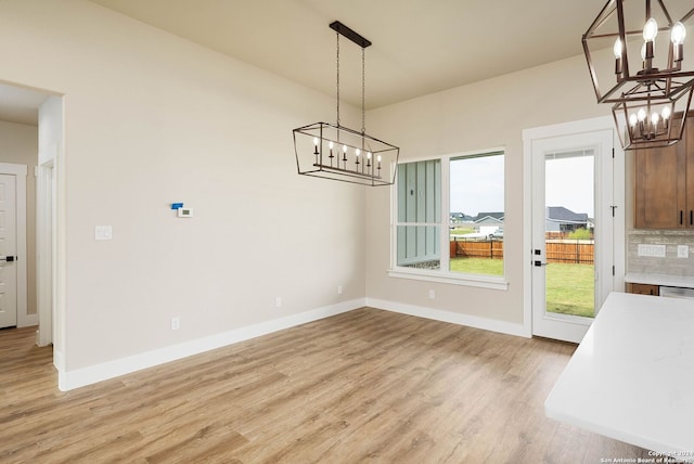 unfurnished dining area with a notable chandelier and light wood-type flooring