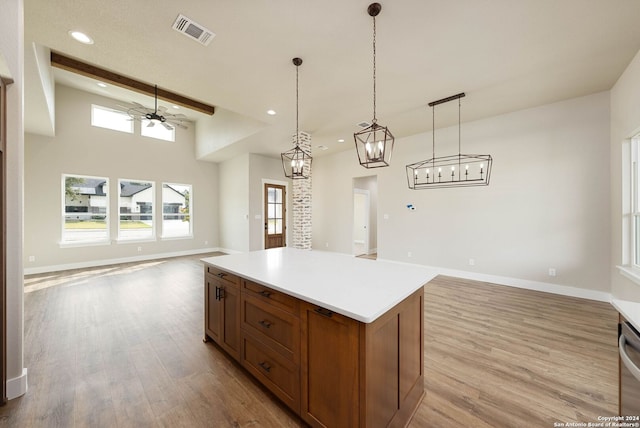 kitchen with hanging light fixtures, light hardwood / wood-style flooring, ceiling fan, beam ceiling, and a kitchen island