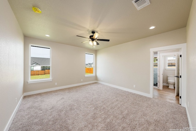 carpeted spare room featuring a textured ceiling, a wealth of natural light, and ceiling fan