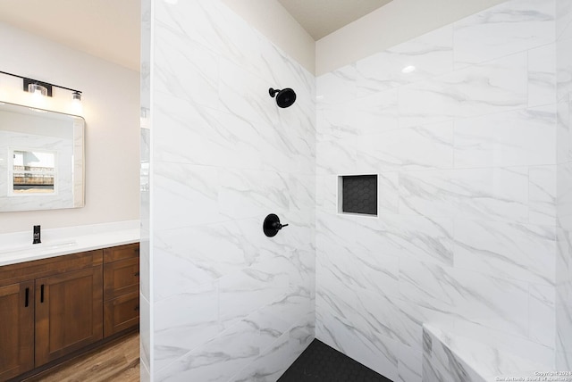 bathroom with tiled shower, vanity, and hardwood / wood-style flooring