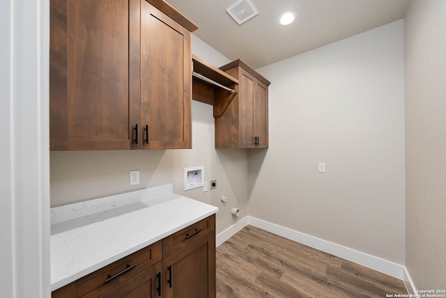 laundry room featuring hookup for an electric dryer, washer hookup, cabinets, hardwood / wood-style flooring, and hookup for a gas dryer