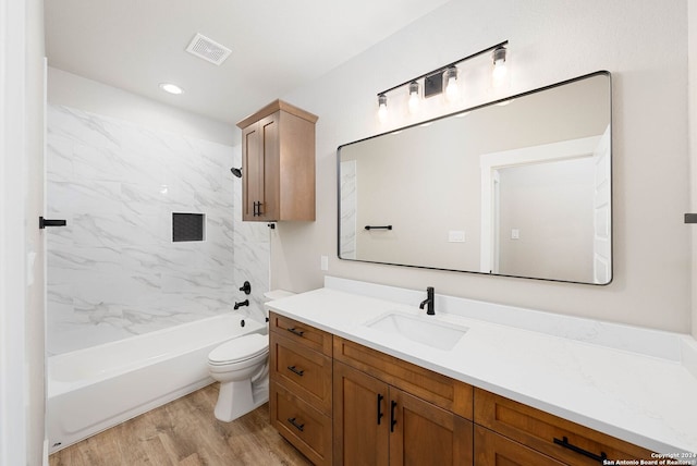 full bathroom with toilet, vanity, wood-type flooring, and tiled shower / bath