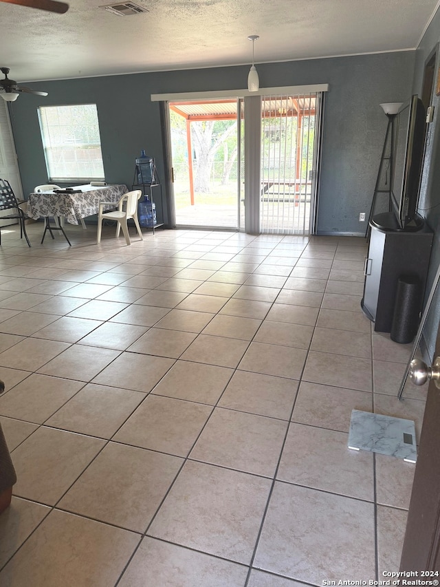 interior space with ceiling fan, a textured ceiling, and light tile patterned floors