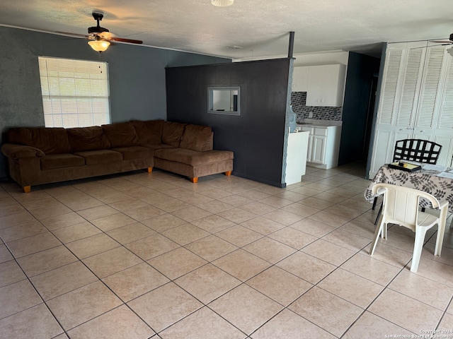 living room with a textured ceiling, ceiling fan, and light tile patterned flooring