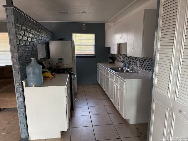 kitchen featuring sink, light tile patterned floors, hanging light fixtures, tasteful backsplash, and stainless steel range with gas cooktop