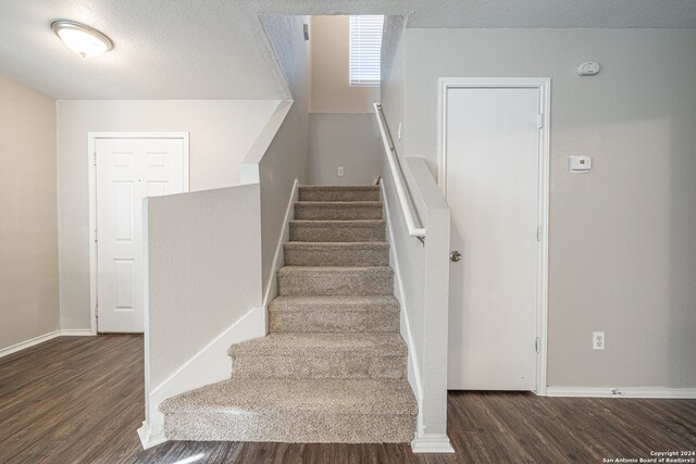 stairs featuring wood-type flooring and a textured ceiling