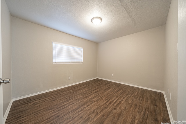 unfurnished room with a textured ceiling and dark wood-type flooring