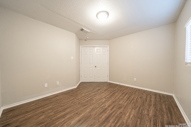 spare room featuring dark hardwood / wood-style floors and a textured ceiling