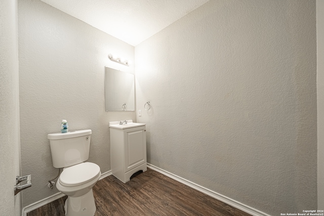 bathroom featuring vanity, wood-type flooring, lofted ceiling, and toilet