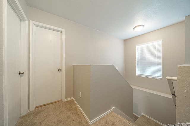 corridor featuring light carpet and a textured ceiling