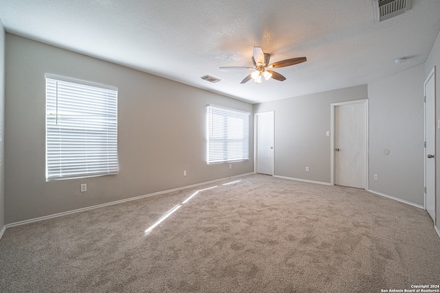 empty room with a textured ceiling, carpet floors, and ceiling fan