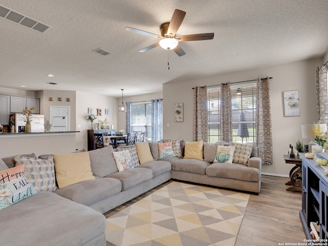 living room featuring a textured ceiling, light hardwood / wood-style floors, and ceiling fan