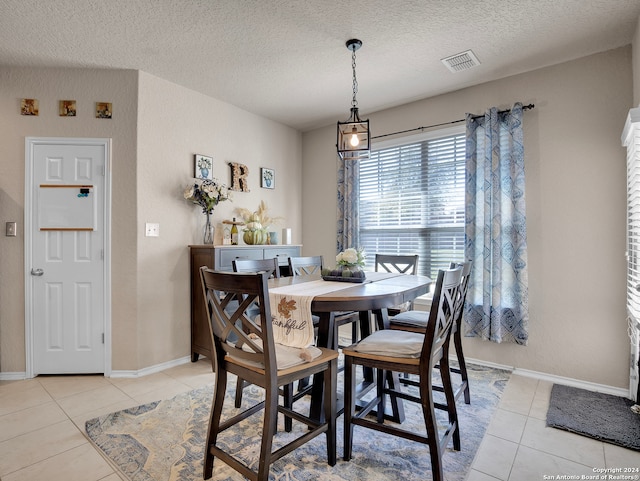 tiled dining room featuring a textured ceiling