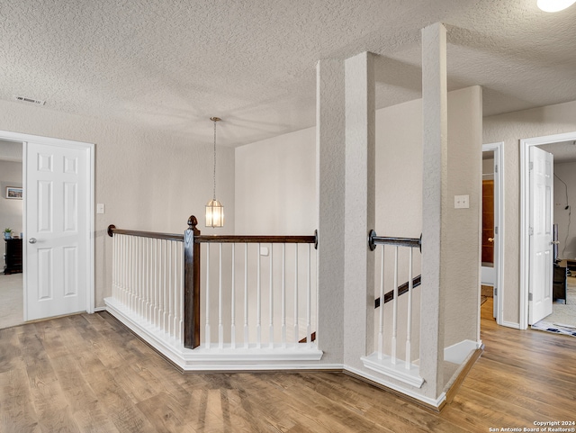 corridor with wood-type flooring and a textured ceiling