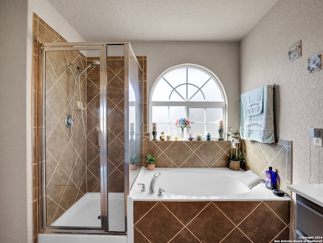 bathroom featuring separate shower and tub, vanity, and a textured ceiling