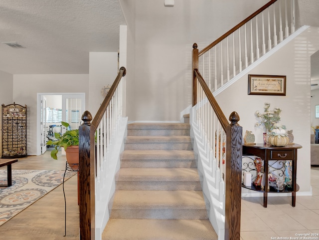 staircase featuring wood-type flooring and a textured ceiling