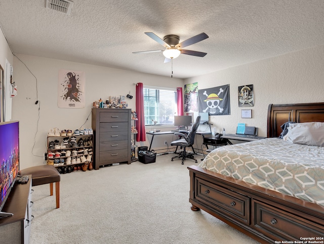 bedroom with ceiling fan, light colored carpet, and a textured ceiling