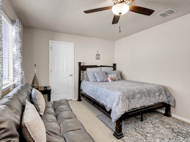 carpeted bedroom featuring ceiling fan and a textured ceiling