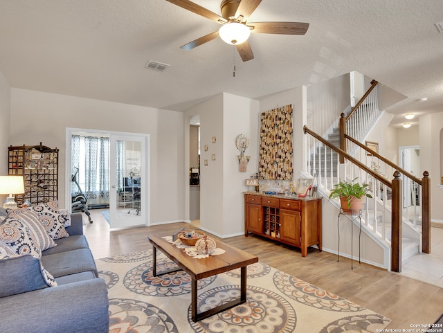 living room featuring ceiling fan, light hardwood / wood-style floors, and a textured ceiling