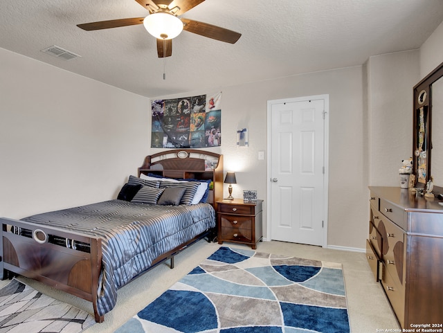 bedroom with light carpet, a textured ceiling, and ceiling fan