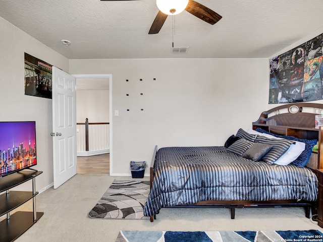 carpeted bedroom featuring a textured ceiling and ceiling fan