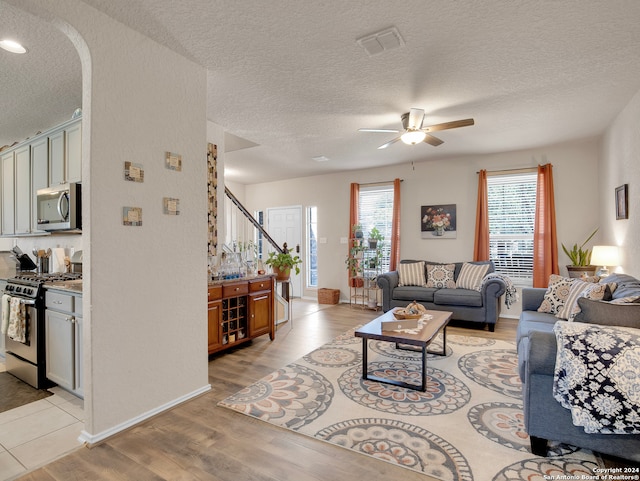 living room featuring a textured ceiling, light hardwood / wood-style floors, and ceiling fan