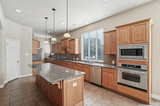 kitchen featuring a kitchen bar, decorative backsplash, stainless steel appliances, decorative light fixtures, and a kitchen island