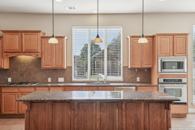 kitchen with decorative backsplash, appliances with stainless steel finishes, hanging light fixtures, and sink