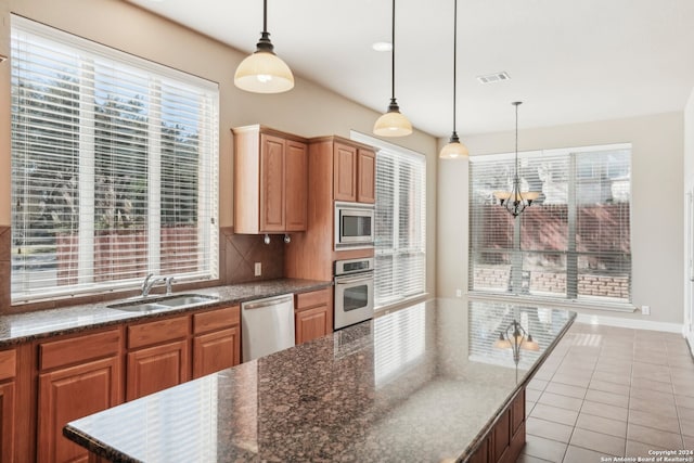 kitchen with sink, hanging light fixtures, stainless steel appliances, a notable chandelier, and decorative backsplash