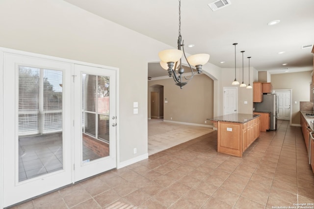 kitchen with a center island, hanging light fixtures, dark stone countertops, stainless steel fridge, and light tile patterned floors